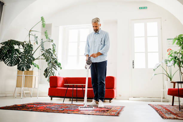 istock Man cleaning house with wireless vacuum cleaner 1411889068