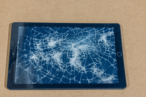 View of electronic tablet with damaged screen isolated on gray background.