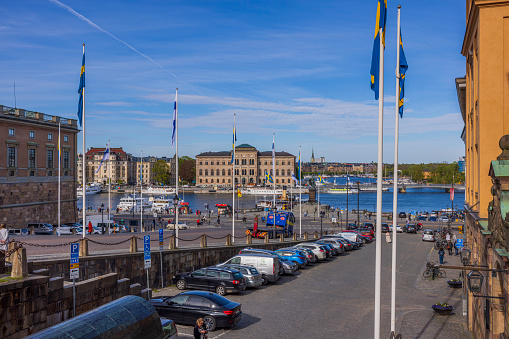 Stockholm. Sweden. Stockholm. 05.18.2022. View of parking lot on square near Royal Palace and of Swedish and Finnish flags on waterfront in downtown Stockholm.