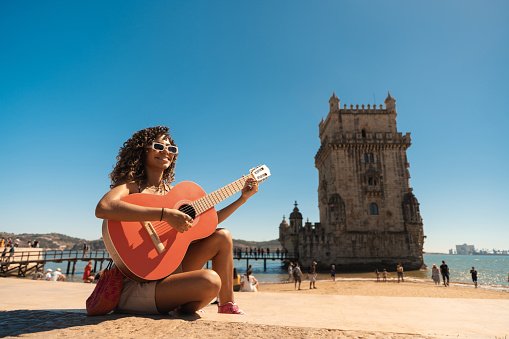 Tourist playing guitar in front of Torre de Belém in LIsbon, Portugal