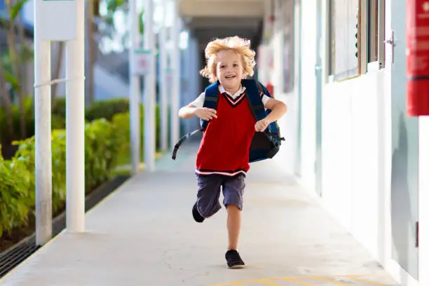 Child going to school. Boy running in school yard. Little student excited to be back to preschool or kindergarten. Beginning of class after vacation. Kids run to parents or friends after lesson.