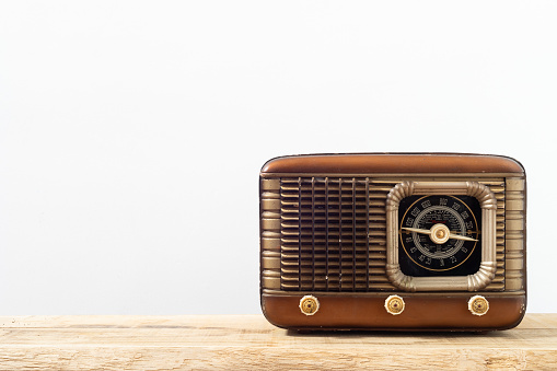 Retro radio receiver on a wooden surface and white background.  Vintage radio with copy space.