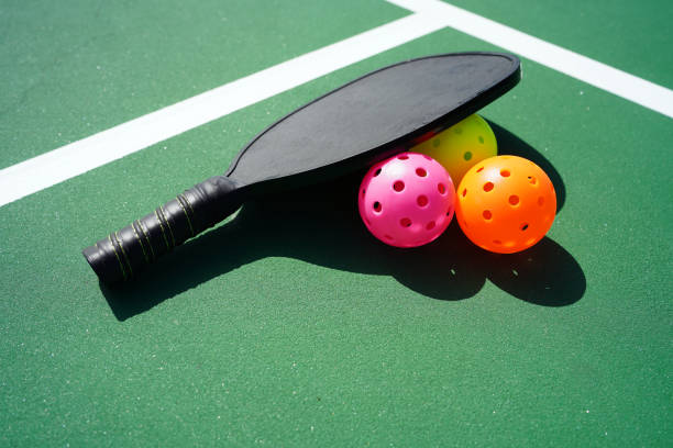 Pickleball Pickleball paddle and several pickle balls on court. pickleball equipment stock pictures, royalty-free photos & images