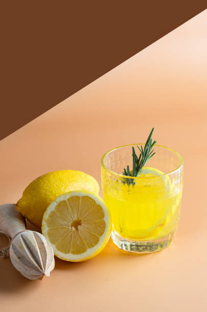 Fresh lemon lemonade, decorated with rosemary  and lemon fruit on beige background. Refreshment beverage for summer hot day.