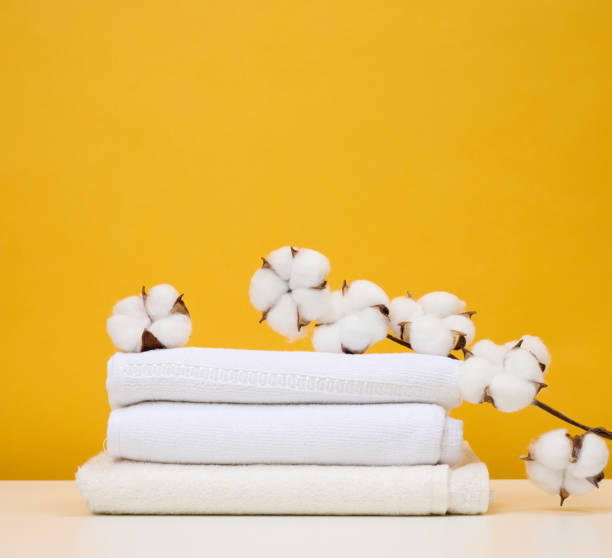 istock Twisted white terry towels on white table, yellow background 1411903354