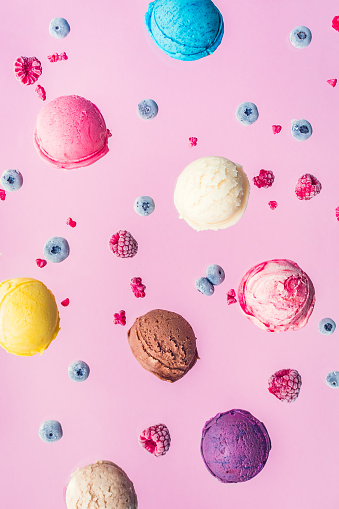 Falling ice cream scoops and berries on pink background. Food levitation. Colorful ice cream art photo.