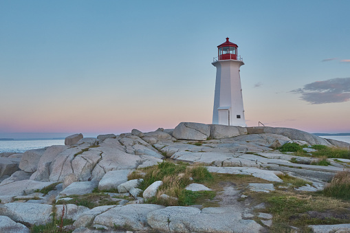 Photograph of the iconic Peggy's Cove lighthouse taken at sunrise on a beautiful summer morning..