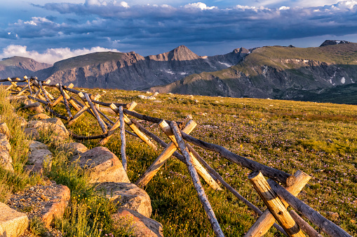 A wooden fence lit by the golden setting sun at the Gore Range Overlook on Trail Ridge Road, Rocky Mountain National Park, Colorado.