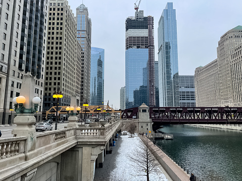 Downtown Chicago Loop in January with snow on riverwalk with very few people and cars during quarantine