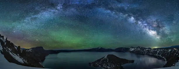 A colorful Milky Way panorama reflects in Crater Lake, captured on the Summer Solstice in Crater Lake National Park, Oregon.
