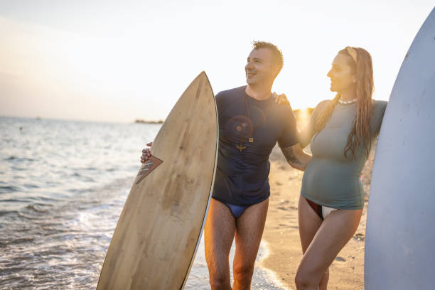 istock Couple surfers stay on sunset beach 1411920812