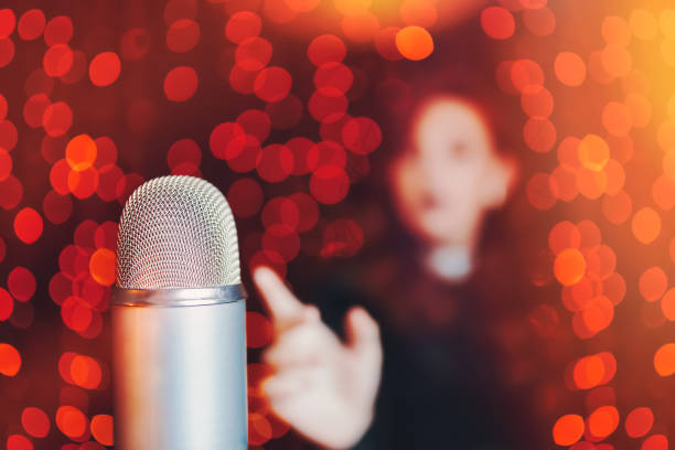 istock Woman pulls hand to microphone for sing at concert. 1411921041