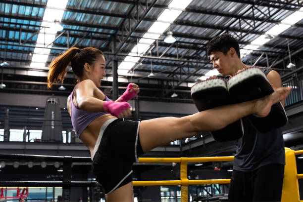 Combat sports and healthy concept. Thai boxing, Muay Thai. Asian woman practicing kicks with male trainer in the gym. Combat sports and healthy concept. Thai boxing, Muay Thai. women boxing sport exercising stock pictures, royalty-free photos & images