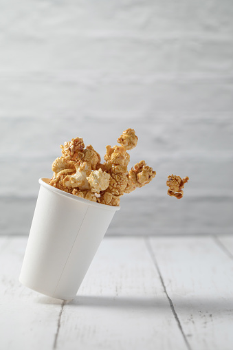 Dropping a small paper cup filled with caramel popcorn