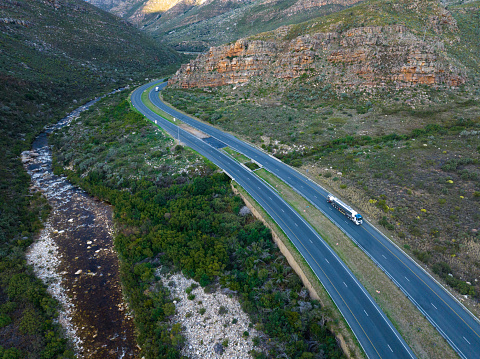 Aerial shot over a large petrol tanker truck travelling towards Cape Town along the National Road. Truck driving through the Hex River Valley. Trucking and freight industry.