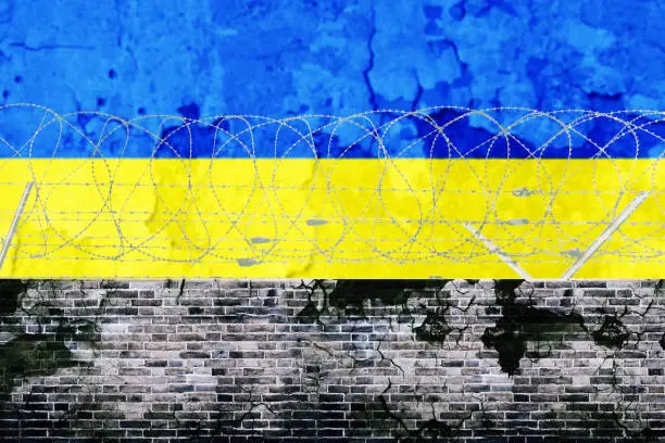 Image of barbed wire wall with Ukraine flag background