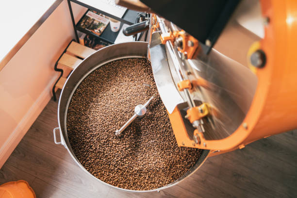 primo piano della torrefazione del caffè con chicchi di caffè nella piccola produzione di caffè - roasted machine bean mixing foto e immagini stock