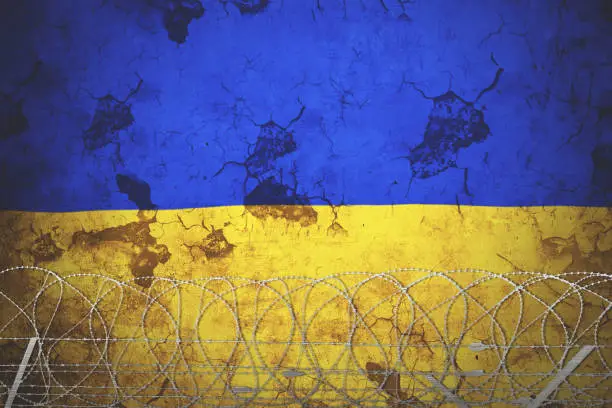 Ukraine national flag with grunge background and barb wire