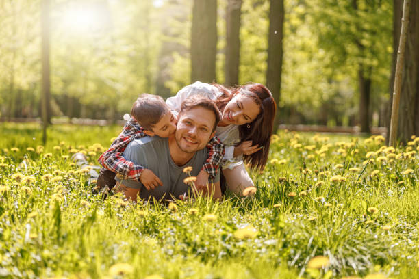 Portrait of happy Caucasian family lying in hugs on green grass in park on sunny summer day. stock photo