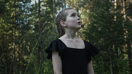 Girl in black dress outdoors in forest area.