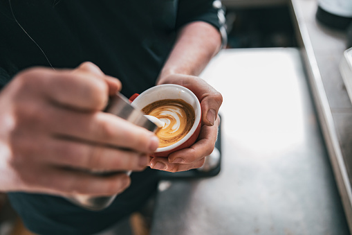 Barista pouring milk in cup of fresh made coffee making latte or cappuccino. High quality photo