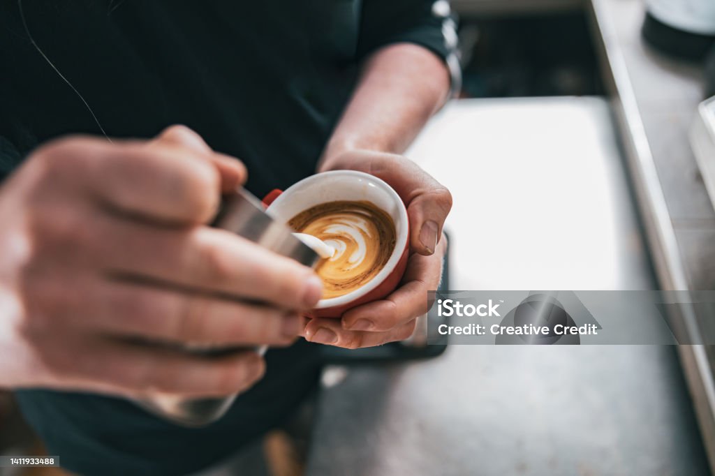 Professional Barista pouring milk in cup of fresh made coffee for making latte or cappuccino Barista pouring milk in cup of fresh made coffee making latte or cappuccino. High quality photo Crema - Coffee Stock Photo