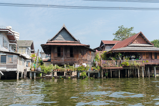 Exteriors of typical residential houses located near khlong flowing in Thonburi district of Bangkok on sunny day