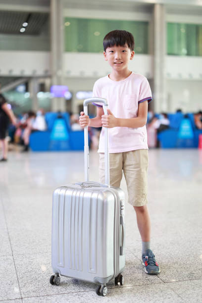 Boy at the airport with suitcase, stock photo