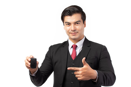 Portrait of a confident business man in black suit feeling happy and smile holding the keys of the car isolated on white background.