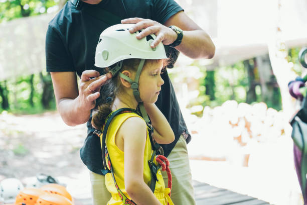 dziecko jest umieszczane na ochronie, aby pokonać przeszkody w parku linowym. - education high up sport sports helmet zdjęcia i obrazy z banku zdjęć