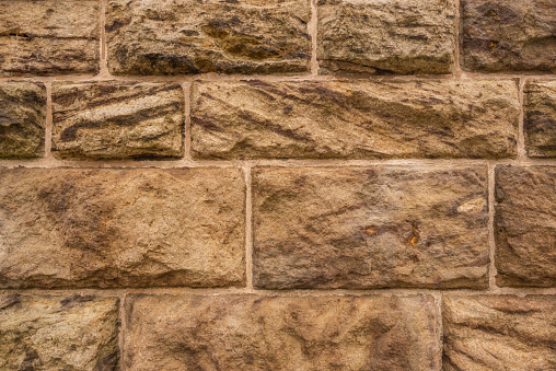 Geometric stone wall background texture, consisting of very large, roughly carved sandstone blocks