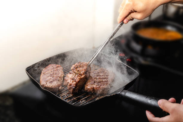 istock Chef cooking beef steak on black pan in the kitchen 1411951151