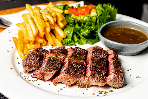 A White Plate of Medium Rare Beefsteak served with French Fried and Salad