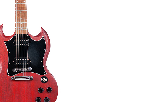 A red electric guitar isolated on white. The miniature musical instrument is standing against the white background.