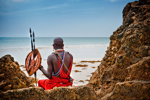 African man of the Maasai tribe in Kenya sits on the ocean and looks into the distance. The flavor of the journey. Travel Culture