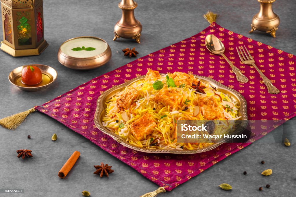 Indian spisy food Paneer Tikka biryani with raita and gulab jamun Served in a dish side view ramdan food on grey background Arab Culture Stock Photo