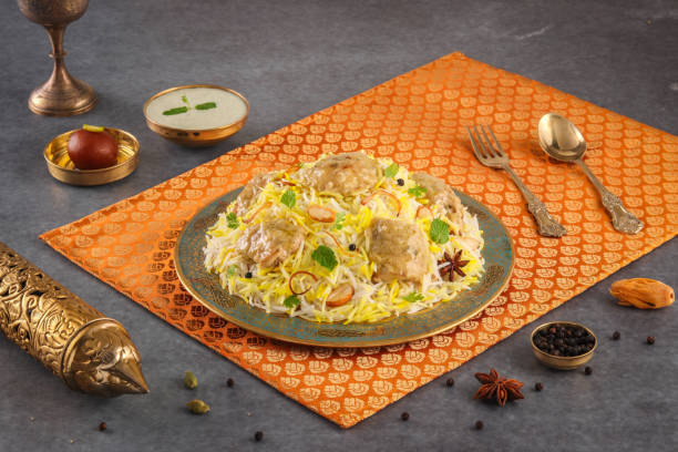 Indian spicy food chicken Afghani Tikka Biryani or Reshmi Chicken Tikka biryani with raita and gulab jamun Served in a dish side view ramdan food on grey background stock photo