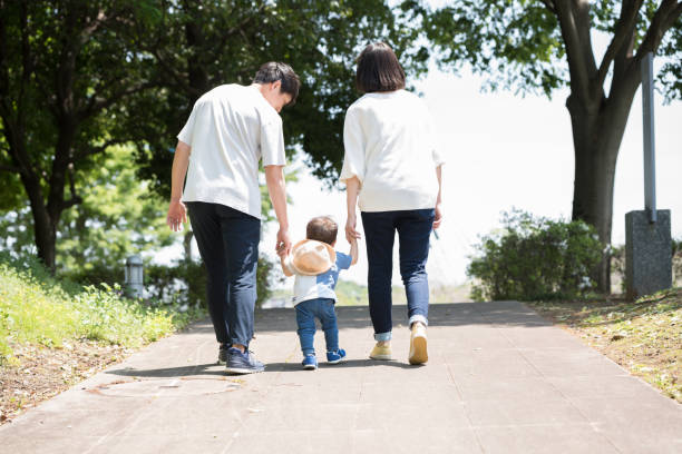 手をつないで歩く3人のアジアの若い家族 - 夫婦 ストックフォトと画像