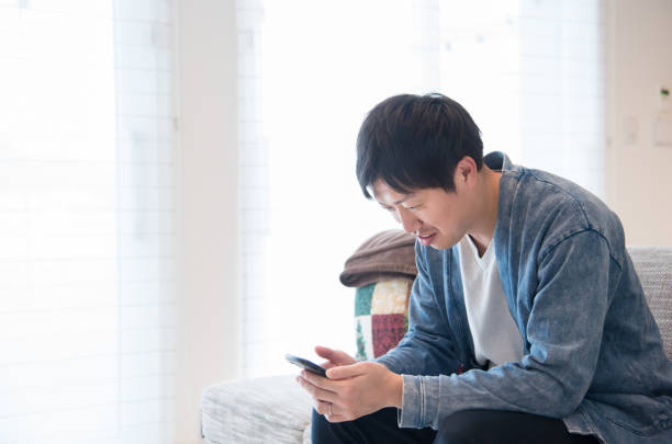 istock man using a smartphone in his living room 1411961200
