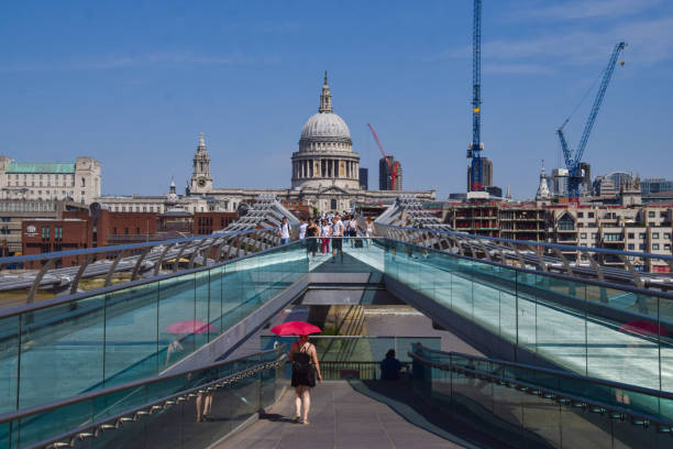 The bridge officially known as the London Millennium Footbridge, is a steel suspension bridge for pedestrians crossing the River Thames in London, England, linking Bankside with the City of London. The image shows the Millennium Bridge and St.Paul's Cathedral with many pedestrians, captured during summer seaosn.