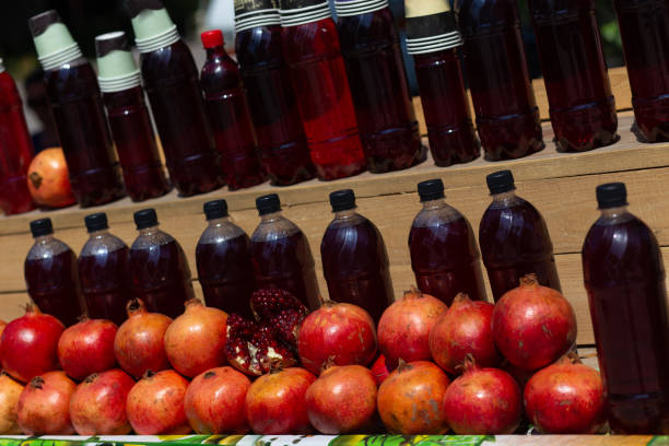 Fresh pomegranates on the market. Pomegranates for juice on the counter of the fruit street market. Freshly squeezed pomegranate juice, bottled in plastic bottles.