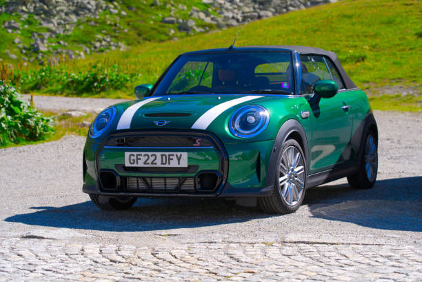 Parked cabriolet sports car at Swiss mountain pass. Dark green English sports car Mini Cooper model S at summit of Swiss mountain Pass Gotthard on a sunny summer day. Photo taken June 25th, 2022, Gotthard Pass, Switzerland. gotthard pass stock pictures, royalty-free photos & images