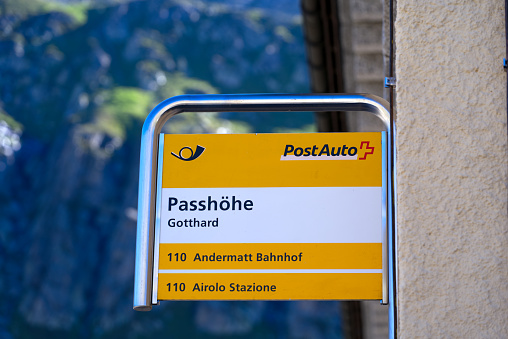 Swiss Post bus staton at mountain pass St. Gotthard with yellow sign on a sunny summer day. Photo taken June 25th, 2022, Gotthard Pass, Switzerland.