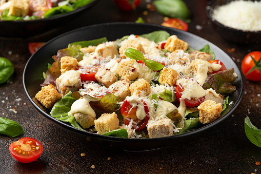 Vegetarian ceasar salad with meat free chicken pieces cherry tomatoes croutons and lettuce.