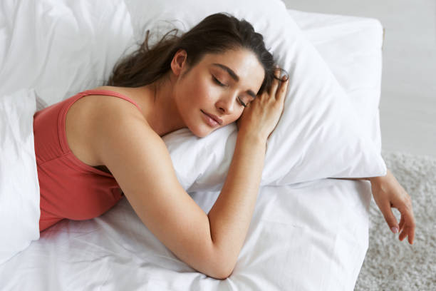 vista dall'alto della bella giovane donna che dorme mentre è sdraiata nel letto - sleeping women bed pillow foto e immagini stock