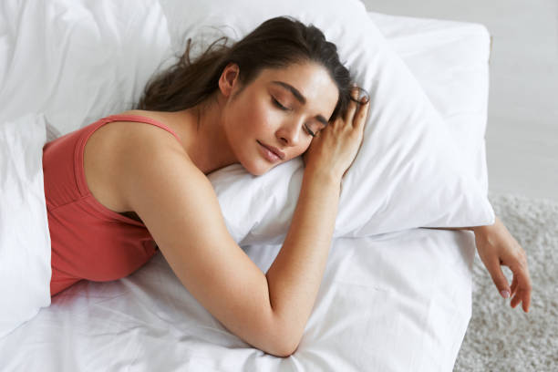 top view of beautiful young woman sleeping while lying in bed - deitando imagens e fotografias de stock