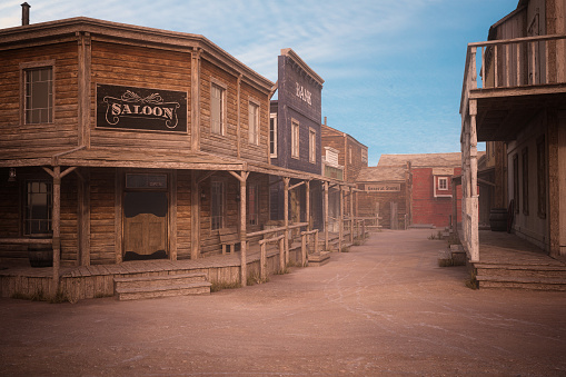Empty dirt street in an old western town with various wooden buildings. 3D rendering.