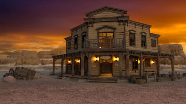 Old wild west saloon in a western desert town at sunset with mountains under orange sky in the background. 3D rendering. stock photo