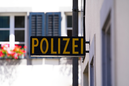 Close-up of black and yellow police (German Polizei) sign at police station at City of Altdorf, Canton Uri, on a sunny summer day.