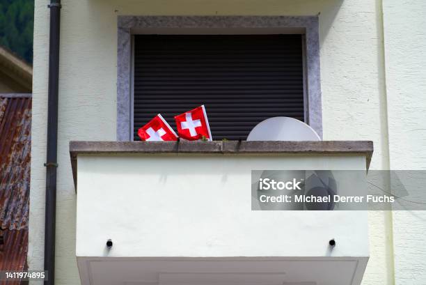 Closeup Of Balcony With Swiss Flags And Satellite Dish On A Sunny Summer Day Stock Photo - Download Image Now
